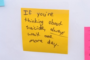 A post-it note with the words 'If you're thinking about suicide, always wait one more day'